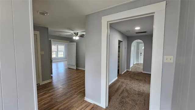 a view of a hallway with wooden floor and a bathroom