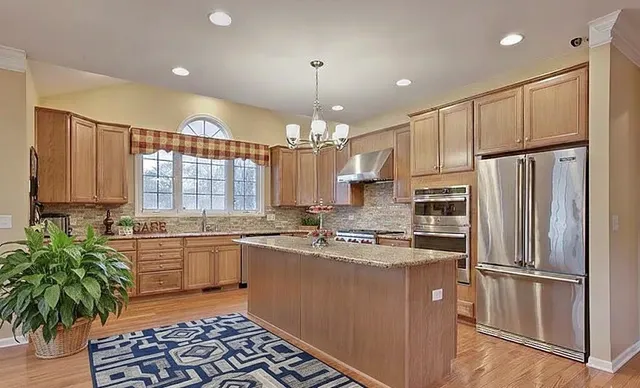a kitchen with kitchen island granite countertop a sink a counter space appliances and cabinets