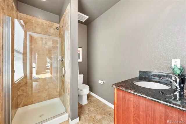 a bathroom with a granite countertop sink toilet and shower
