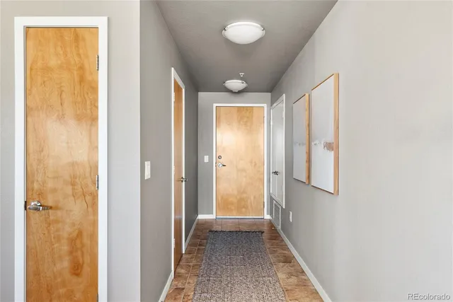 a view of a hallway with wooden floor and a bathroom