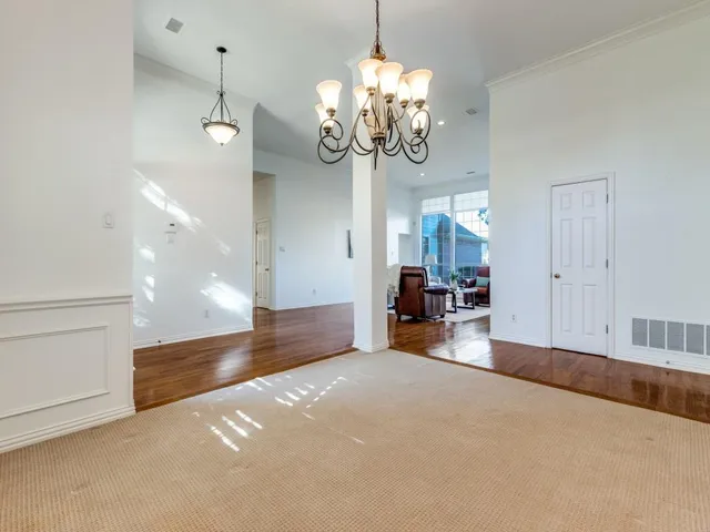 a view of a livingroom with a chandelier fan and kitchen view