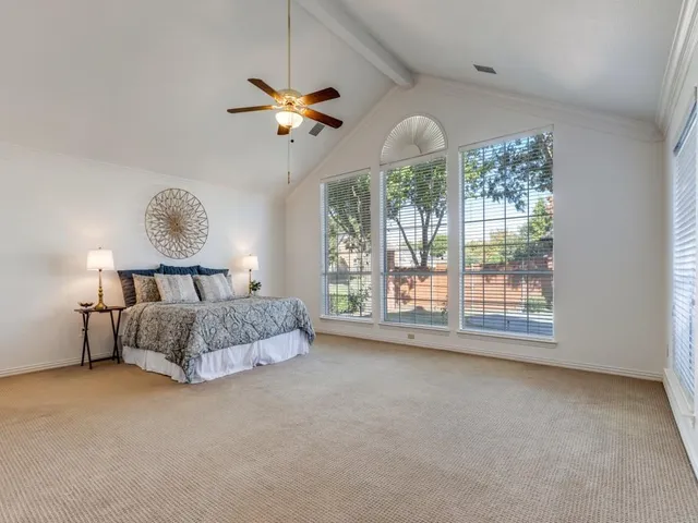 a spacious bedroom with a bed chandelier and window