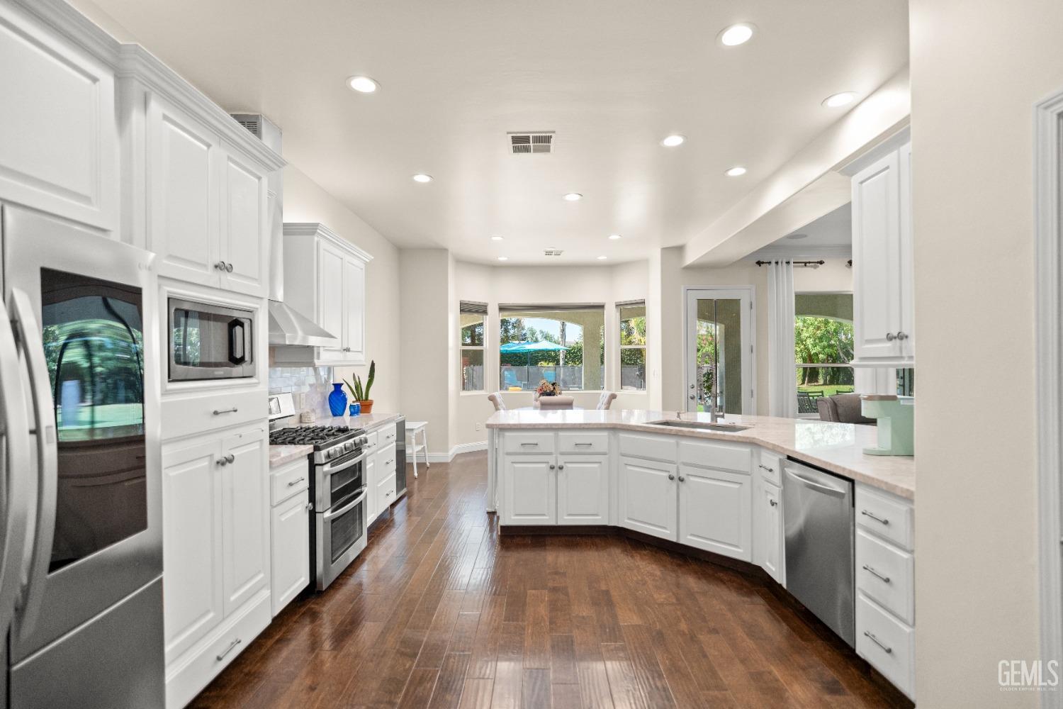 Undisclosed Address Bakersfield, CA 93311 - Photo 5 of 53 a kitchen with stainless steel appliances granite countertop a stove top oven a sink a refrigerator and white cabinets with wooden floor