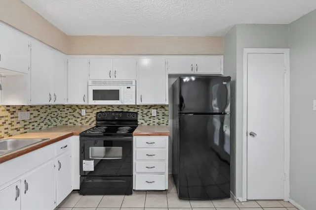 a kitchen with appliances a refrigerator and cabinets