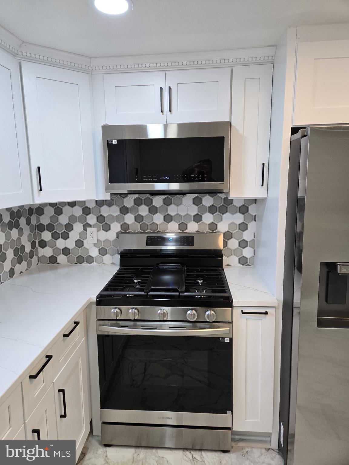 1016 Middleborough Road Essex, MD 21221 - Photo 8 of 33 a kitchen with stainless steel appliances a stove a microwave a refrigerator and cabinets