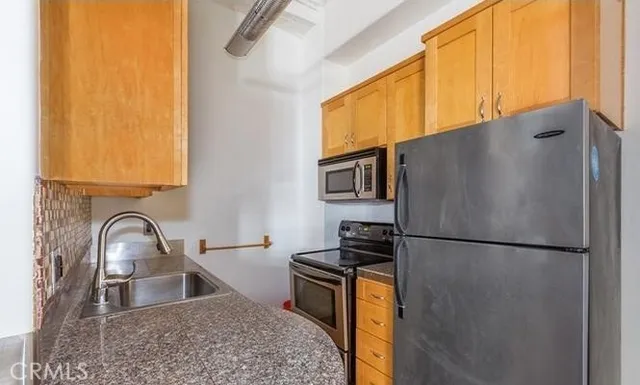 a kitchen with stainless steel appliances granite countertop a refrigerator a sink and a stove