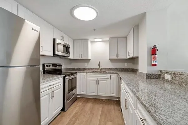 a kitchen with granite countertop a sink stove and refrigerator
