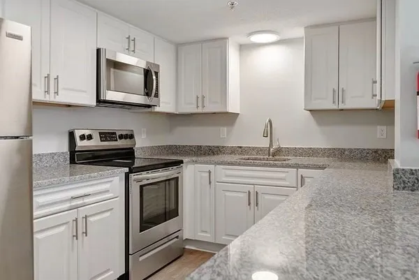 a kitchen with white cabinets granite counter tops and a stove