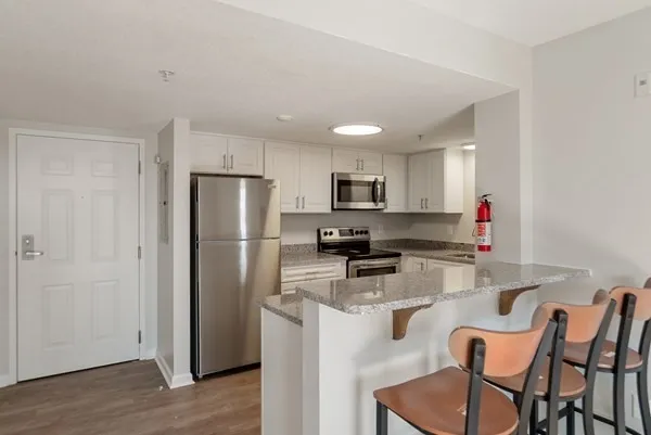 a kitchen with stainless steel appliances granite countertop a refrigerator a stove a sink dishwasher and a refrigerator with wooden floor