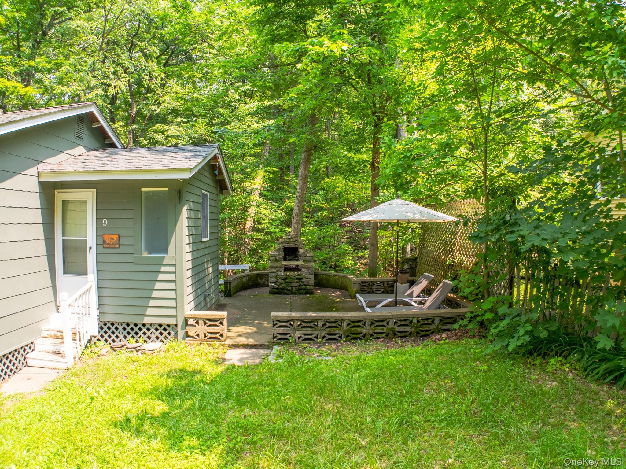 9 Higgins Trail Monroe, NY 10950 - Photo 2 of 24 a backyard of a house with table and chairs under an umbrella