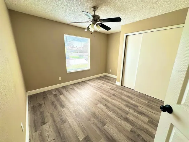 a view of an empty room with a window and wooden floor