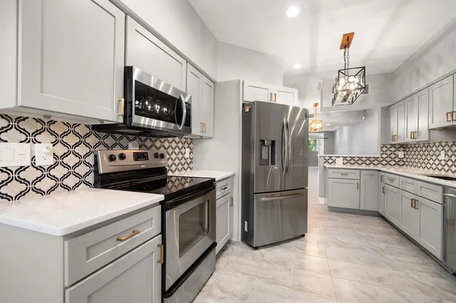 a kitchen with granite countertop a refrigerator stove and microwave