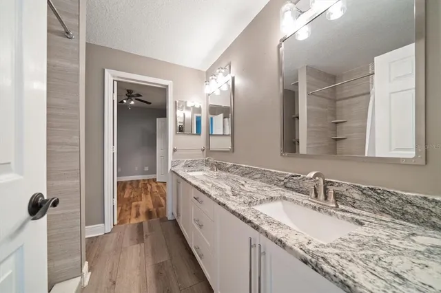 a spacious bathroom with a granite countertop sink a mirror and shower