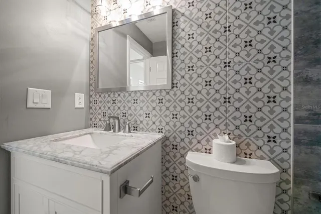 a bathroom with a granite countertop bathtub shower sink vanity and toilet