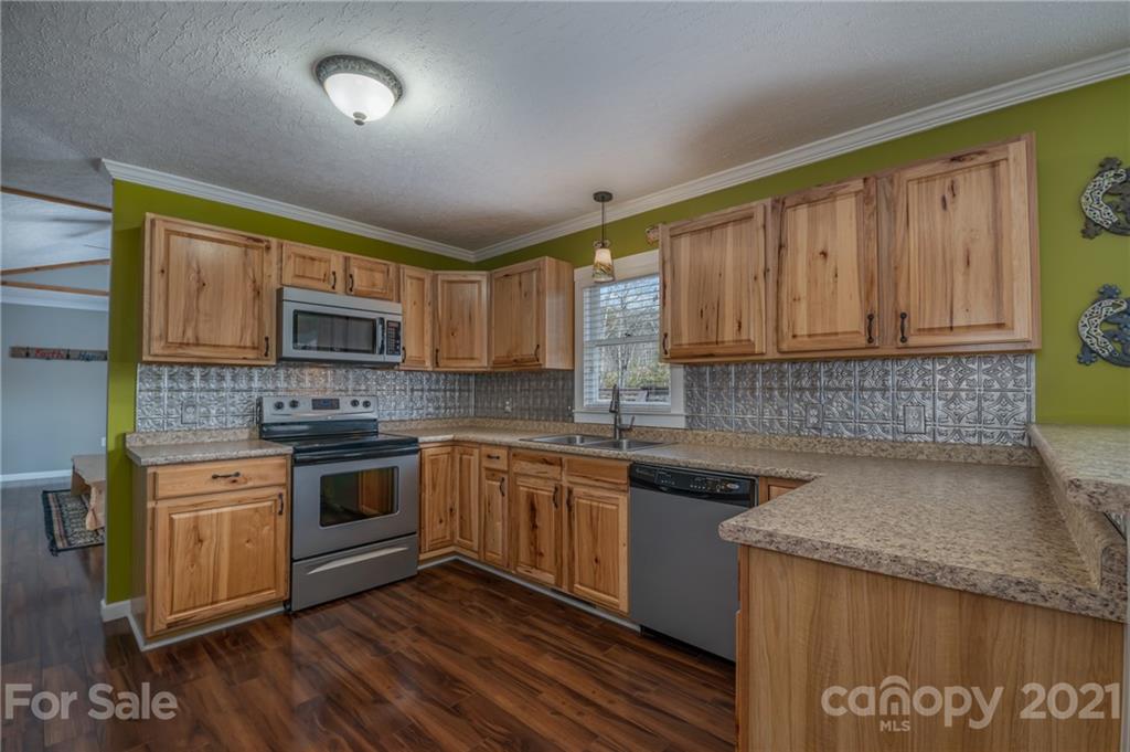 50 Owl Hollow Road Mill Spring, NC 28756 - Photo 29 of 45 a kitchen with stainless steel appliances granite countertop wooden cabinets a stove top oven a sink and dishwasher with wooden floor