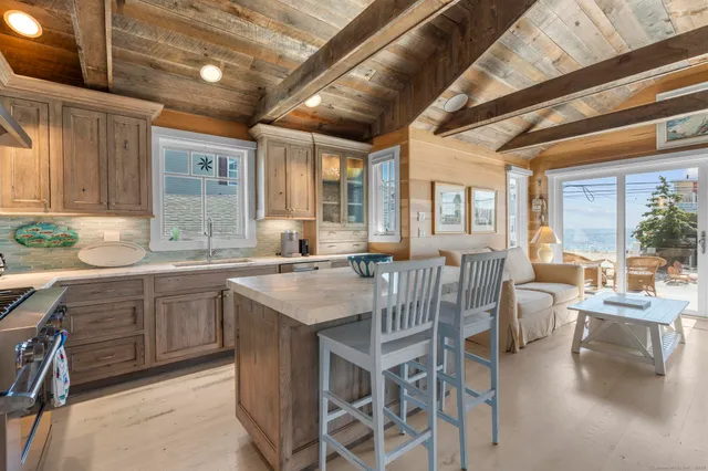 a dining hall with stainless steel appliances granite countertop a stove a sink dishwasher a dining table and chairs with wooden floor