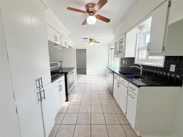 a large white kitchen with stainless steel appliances a sink stove and cabinets