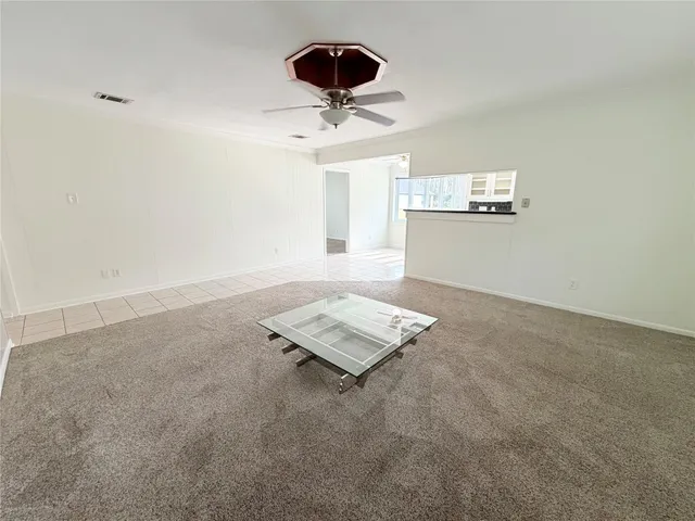 an empty room with a ceiling fan and window