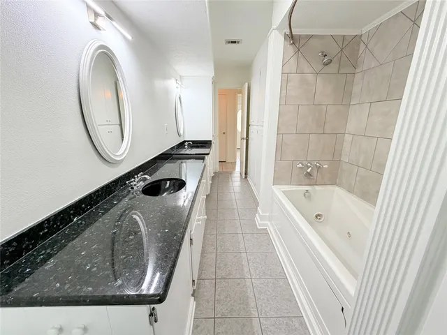 a bathroom with a granite countertop sink a mirror and bathtub