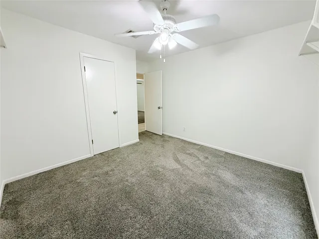 an empty room with a chandelier fan and closet