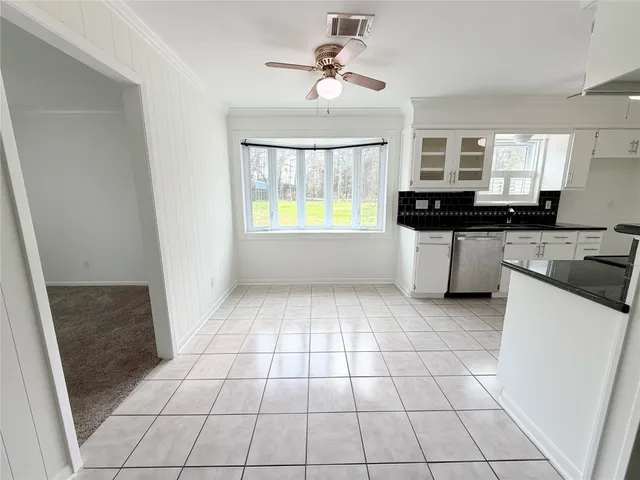 a large white kitchen with a stove a sink a microwave and cabinets
