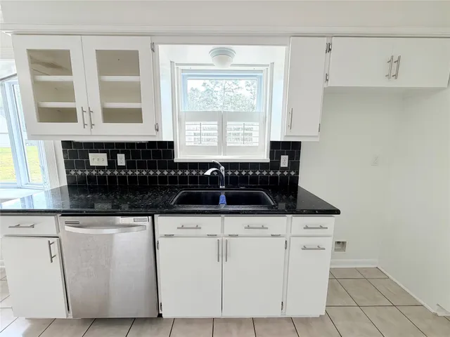 a kitchen with granite countertop white cabinets and sink