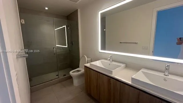a bathroom with a double vanity sink toilet and shower