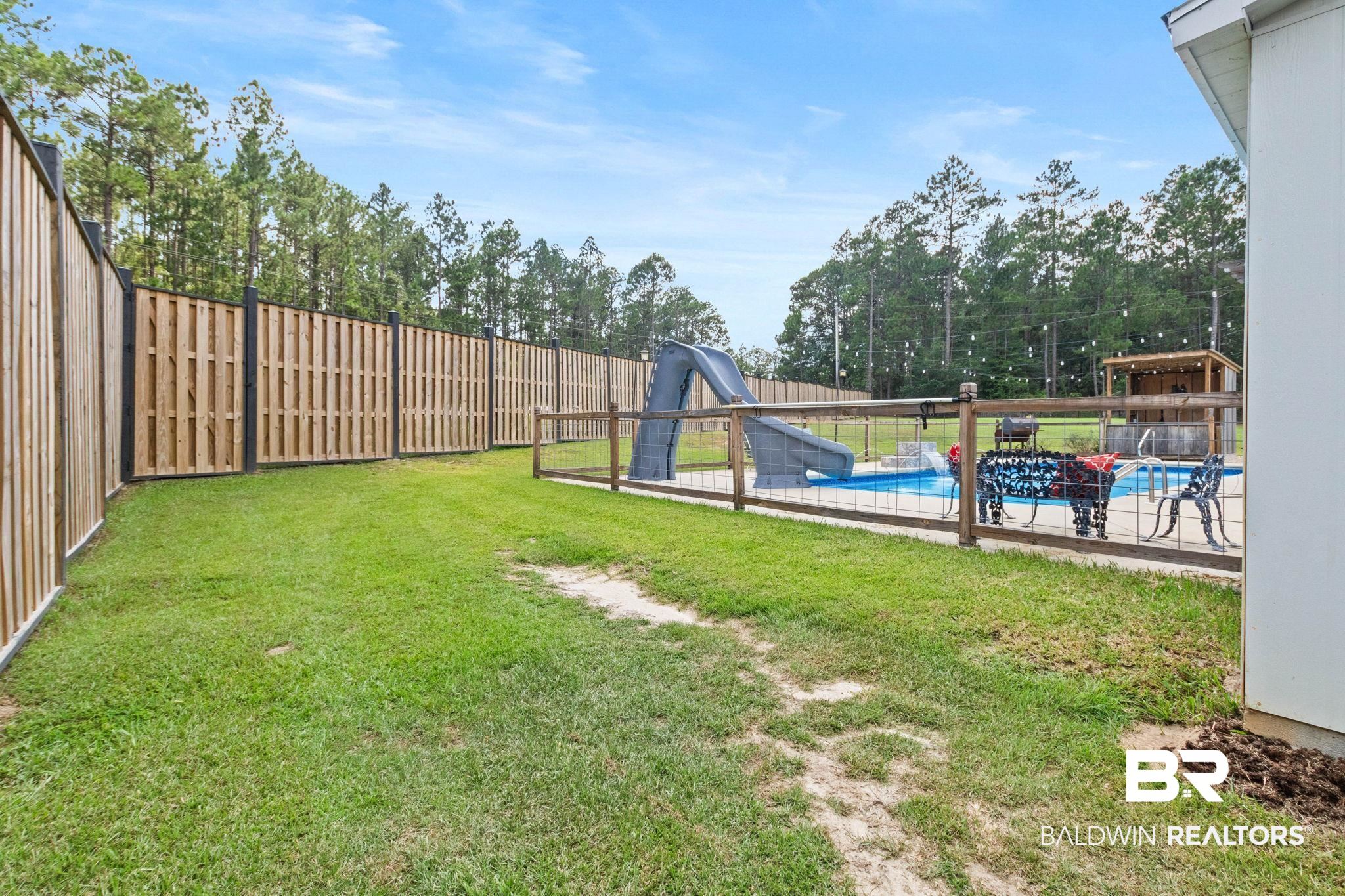 79 Whitetail Run Chatom, AL 36518 - Photo 64 of 82 Expansive backyard featuring a partial privacy fence and an in-ground swimming pool with a slide