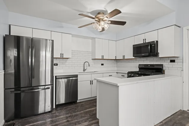 a kitchen with stainless steel appliances a refrigerator a stove a sink and white cabinets