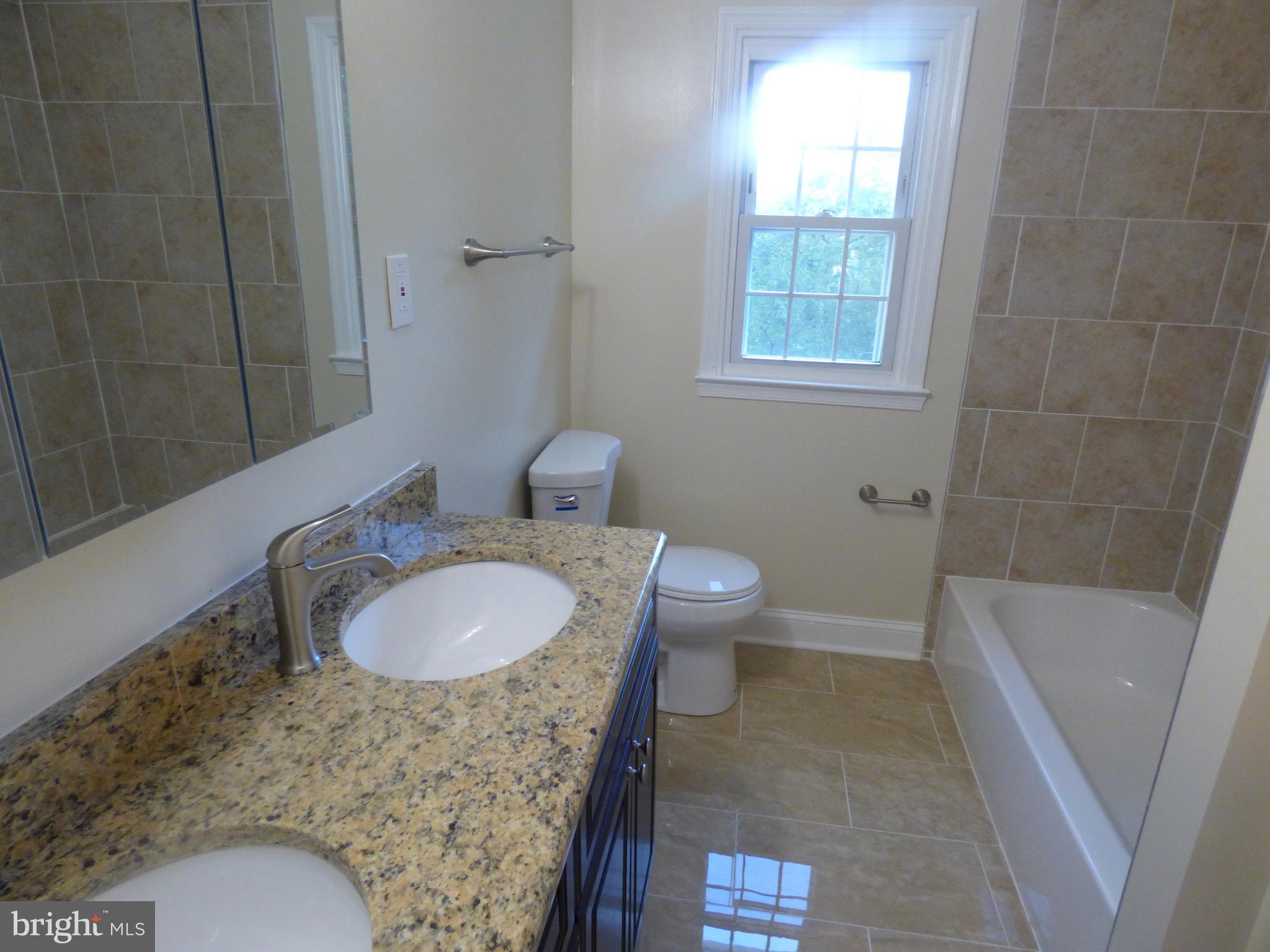 5033 Durham Road West Columbia, MD 21044 - Photo 22 of 30 a bathroom with a granite countertop sink toilet a mirror and shower