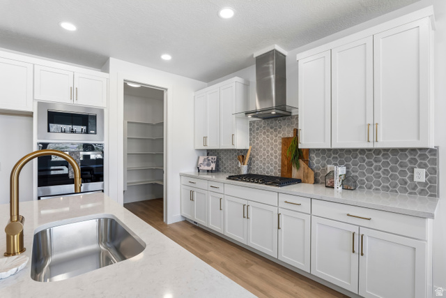 624 North Legend Circle, Unit 480 Mapleton, UT 84664 - Photo 20 of 34 Kitchen featuring light wood-type flooring, white cabinetry, light stone counters, stainless steel appliances, and tasteful backsplash
