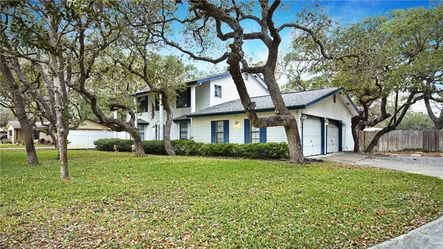 a view of a brick house with a big yard and large trees