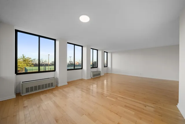a view of an empty room with a window and wooden floor