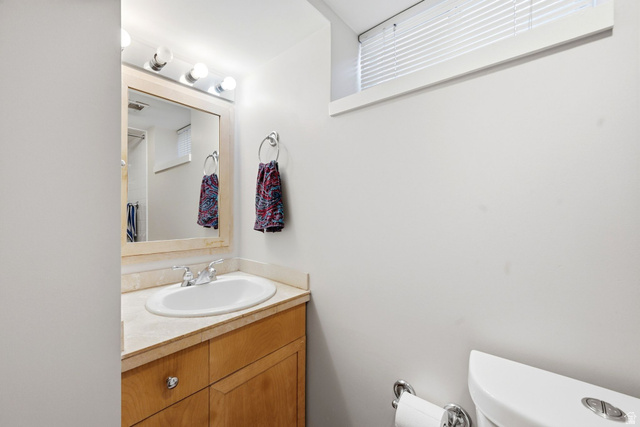 310 East 600 South Centerville, UT 84014 - Photo 20 of 41 Bathroom vanity featuring a light wood cabinet, integrated sink, and a light-toned countertop