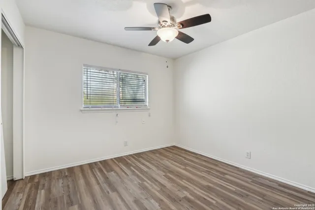an empty room with a window and a ceiling fan