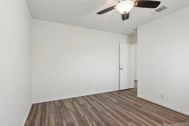 an empty room with wooden floor chandelier fan and closet