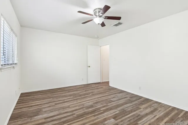 a view of a room with wooden floor and a ceiling fan