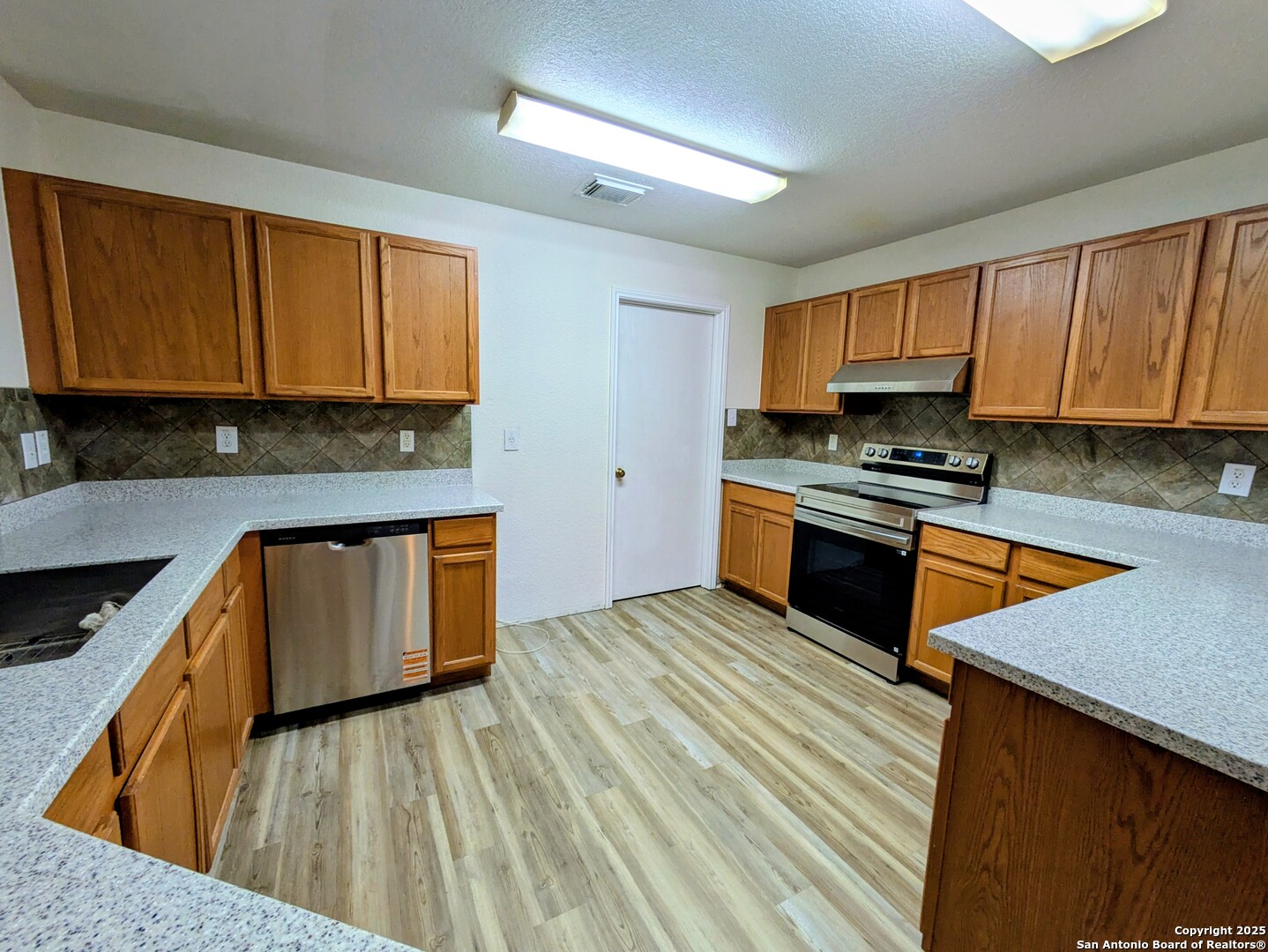 16216 Ike Lane Selma, TX 78154 - Photo 8 of 40 a kitchen with stainless steel appliances granite countertop wooden cabinets a stove top oven a sink and dishwasher