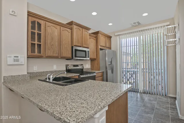 a kitchen with kitchen island granite countertop stainless steel appliances a sink stove refrigerator and cabinets