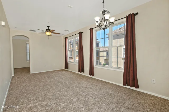 a view of a livingroom with a chandelier fan and windows