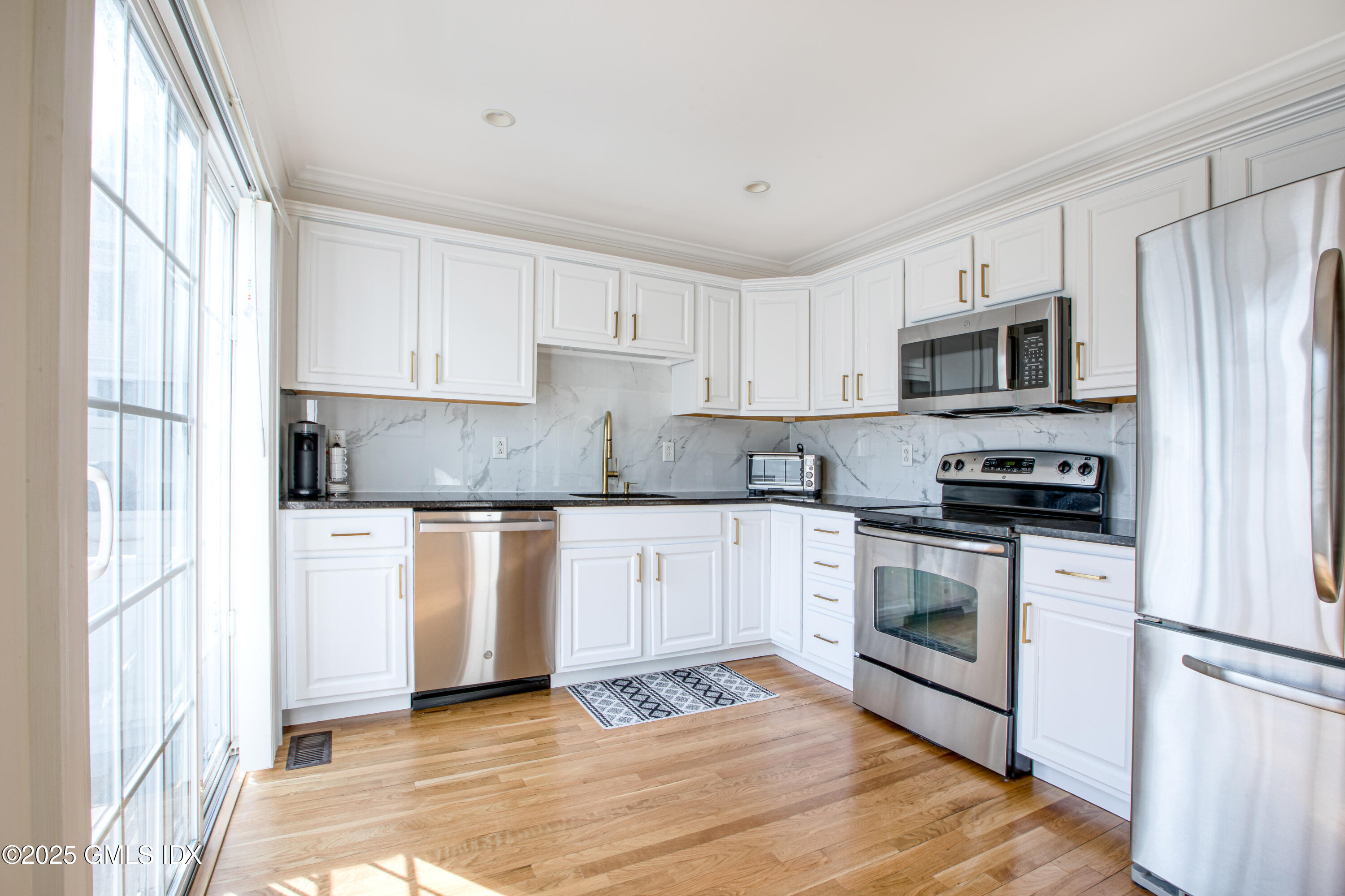 39 Maple Tree Avenue, Unit 16 Stamford, CT 06906 - Photo 5 of 21 a kitchen with granite countertop a refrigerator oven a sink and white cabinets