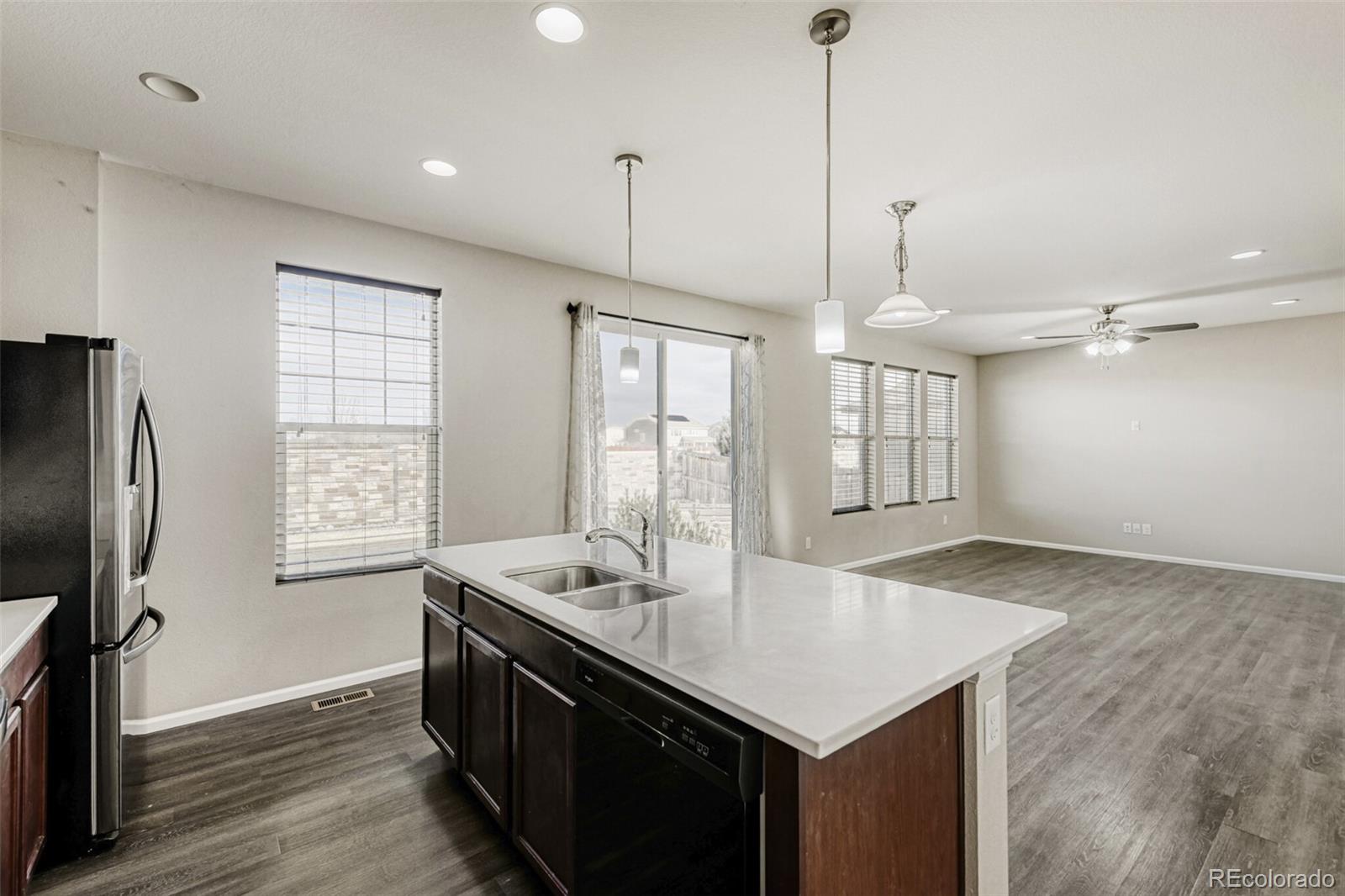 2725 East 159th Way Thornton, CO 80602 - Photo 14 of 36 a kitchen with stainless steel appliances granite countertop a sink a window and wooden floor