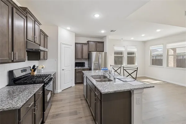 a kitchen with stainless steel appliances a dining table chairs refrigerator and microwave