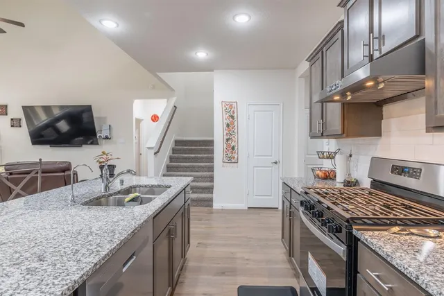 a kitchen with stainless steel appliances granite countertop a sink stove and refrigerator