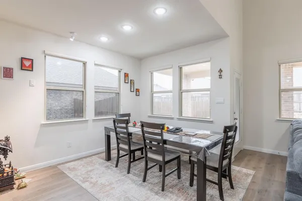 a room with stainless steel appliances lots of white furniture wooden floor and a view of kitchen