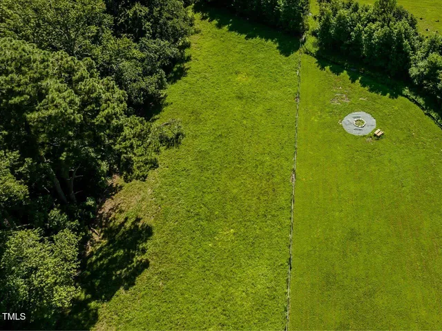 an aerial view of a residential houses with outdoor space and trees all around