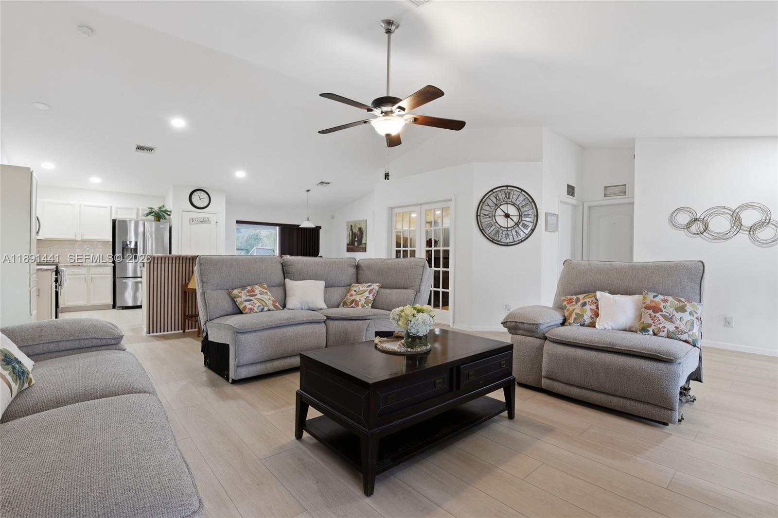 a living room with furniture a clock and a ceiling fan