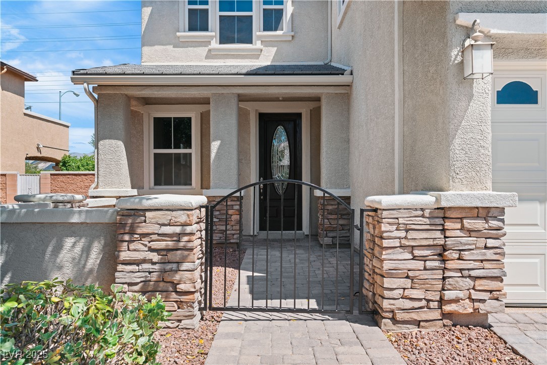 312 Pocono Ranch Avenue North Las Vegas, NV 89031 - Photo 34 of 34 Doorway to property featuring fence, stone siding, stucco siding, and a gate