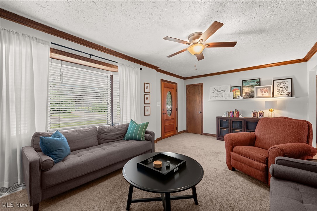1605 Lander Road Cleveland, OH 44124 - Photo 15 of 38 Living area featuring a textured ceiling, light carpet, crown molding, and ceiling fan