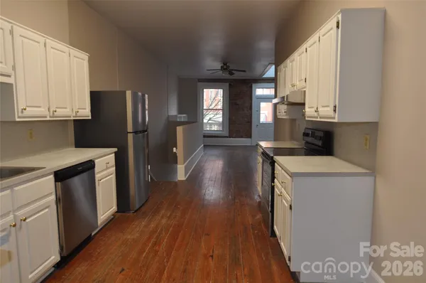 a kitchen with a refrigerator a stove top oven and wooden floors
